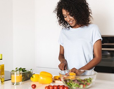 Woman cutting vegetables for salad at kitchen counter