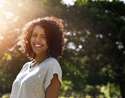 a smiling woman standing in a park