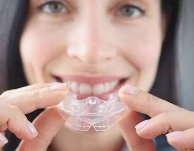 Woman holding nightguard in from of her mouth