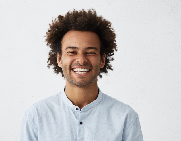 Man in light blue shirt grinning