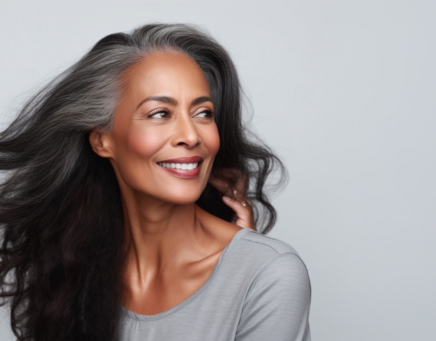 Woman with long dark hair smiling and looking off to the side