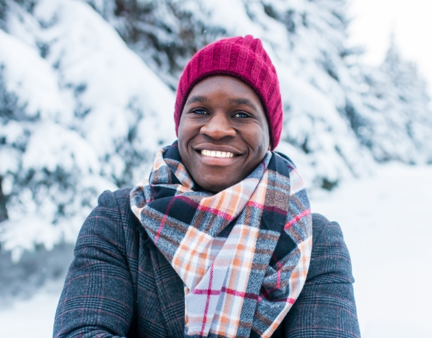 Man in winter clothes smiling with snowy trees in background