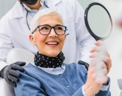 Woman in denim jacket admiring her smile in mirror