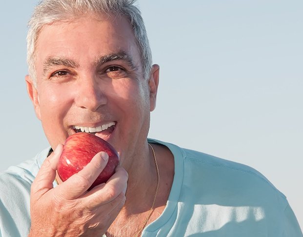 Older man biting into an apple