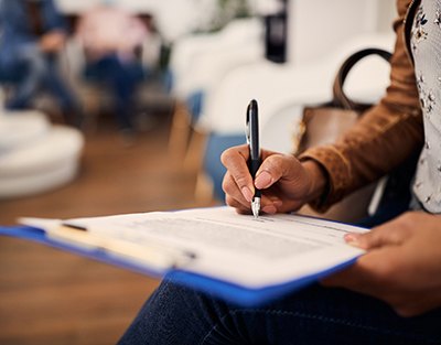 Woman’s hands filling out forms on clipboard with pen