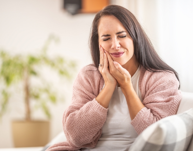 Woman holding her cheek in pain before emergency dentistry in Castle Rock