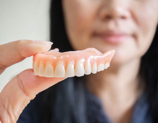 Dentist holding a full upper denture