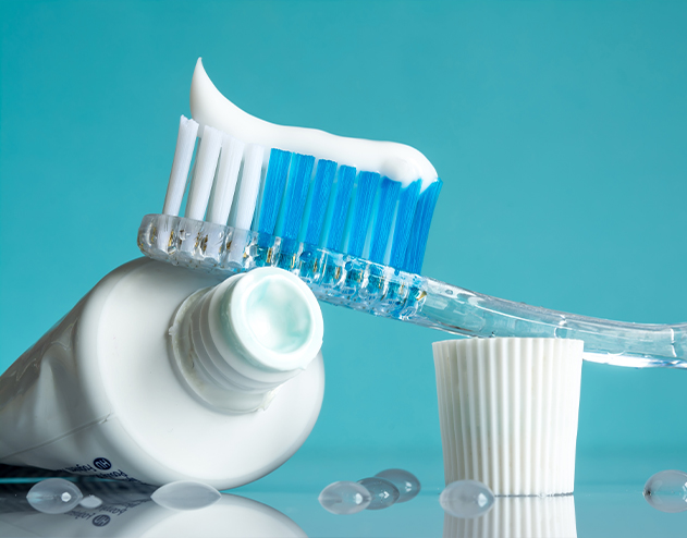 Toothbrush next to open tube of toothpaste