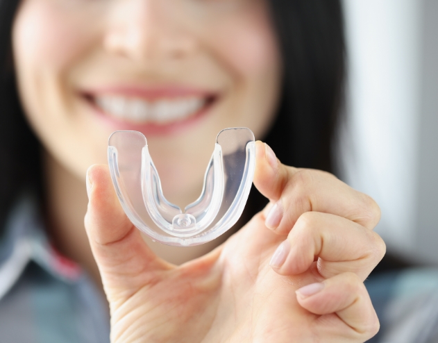 Smiling woman holding a clear nightguard tray