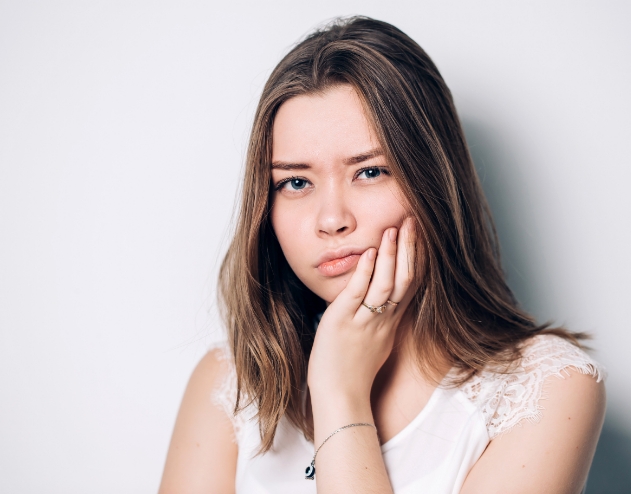 Young woman holding her cheek in pain