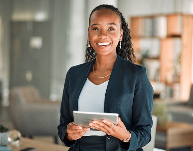 Woman smiling while holding tablet in office