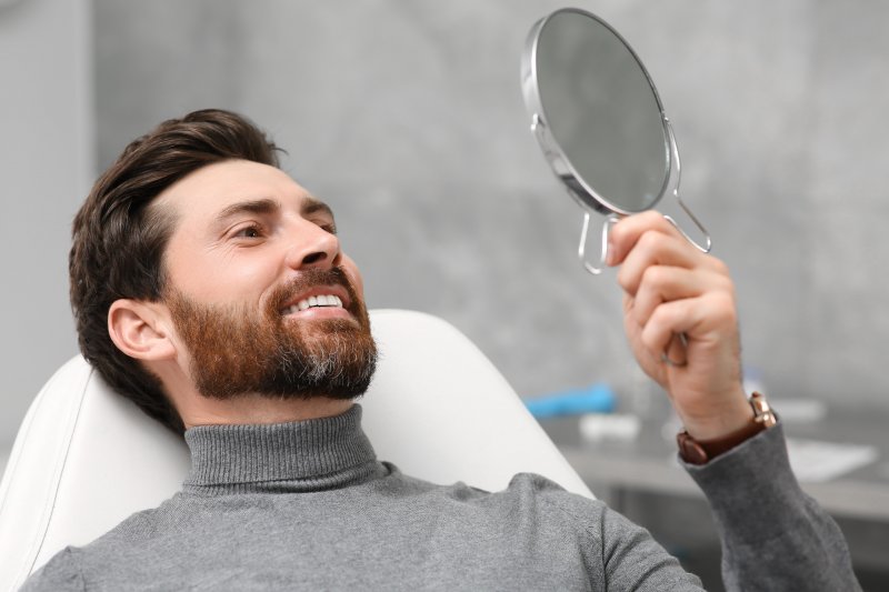 Patient smiling in a mirror after dental fillings