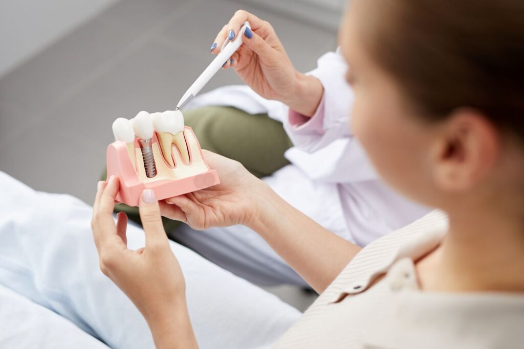 A dentist showing a patient a dental implant model