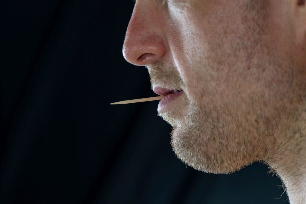 Nose-to-chin profile view of man with toothpick in mouth with black background