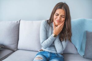 Woman wincing in pain holding side of her face. 