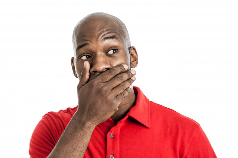 Patient holding mouth in shock after dental bridge fell out