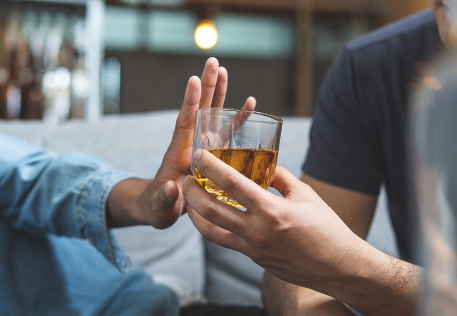 Hand pushing glass of alcohol away